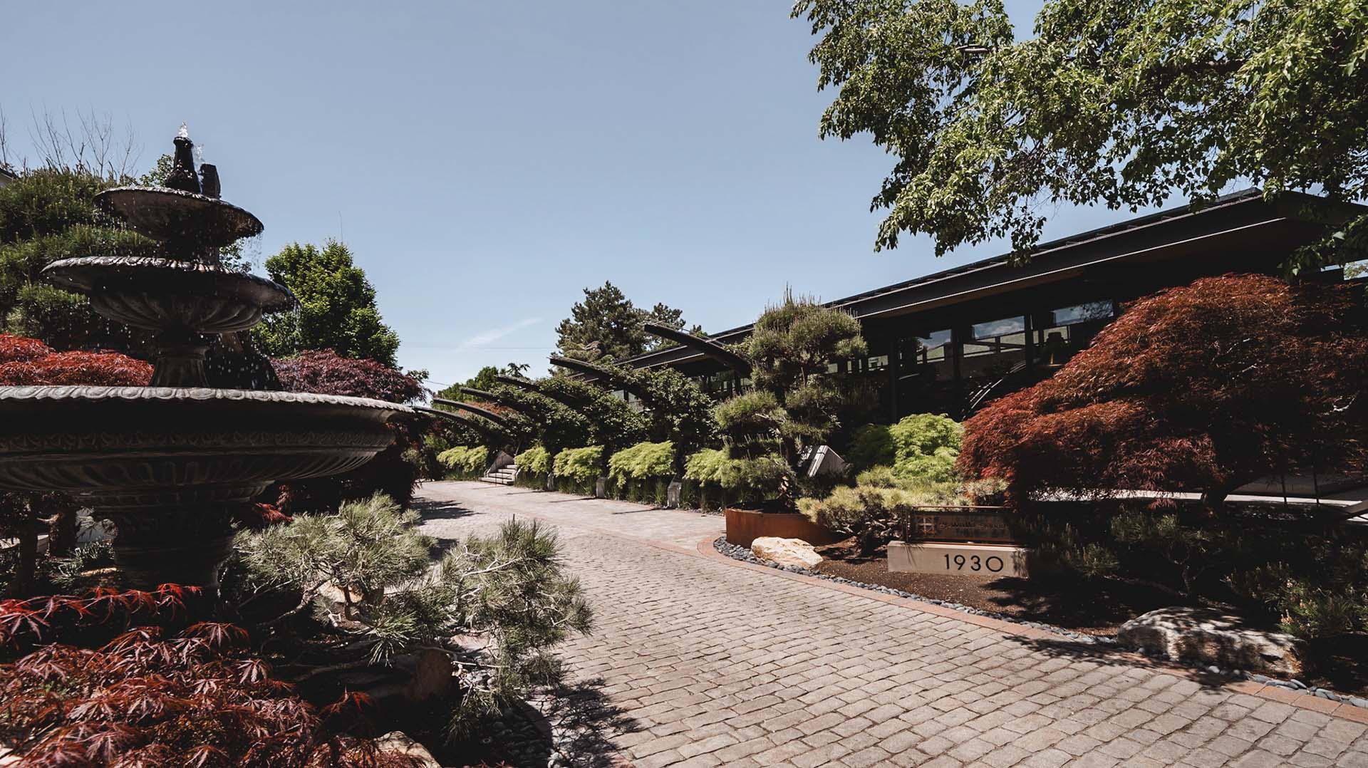 Lush gardens with stone paver walkways and fountains.